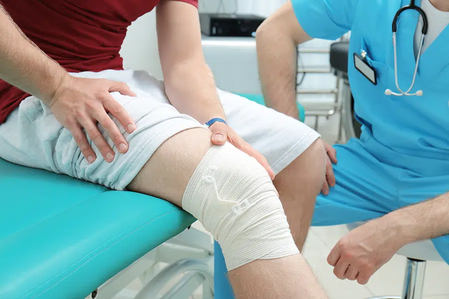 A doctor examining an injured patient wearing a knee wrap.