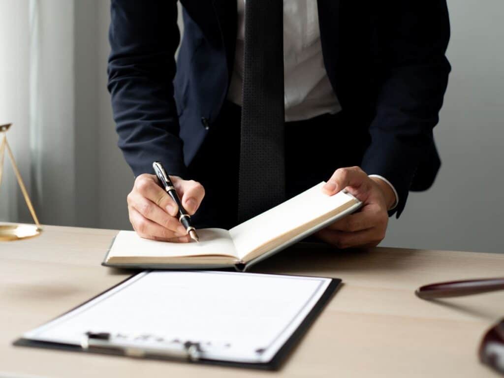 A personal injury attorney writing in a notebook about a case.