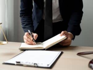 A personal injury attorney writing in a notebook about a case.