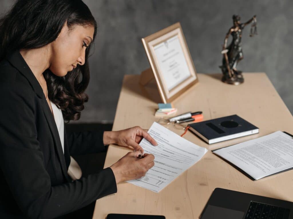 A female personal injury attorney signing legal documents at her desk.