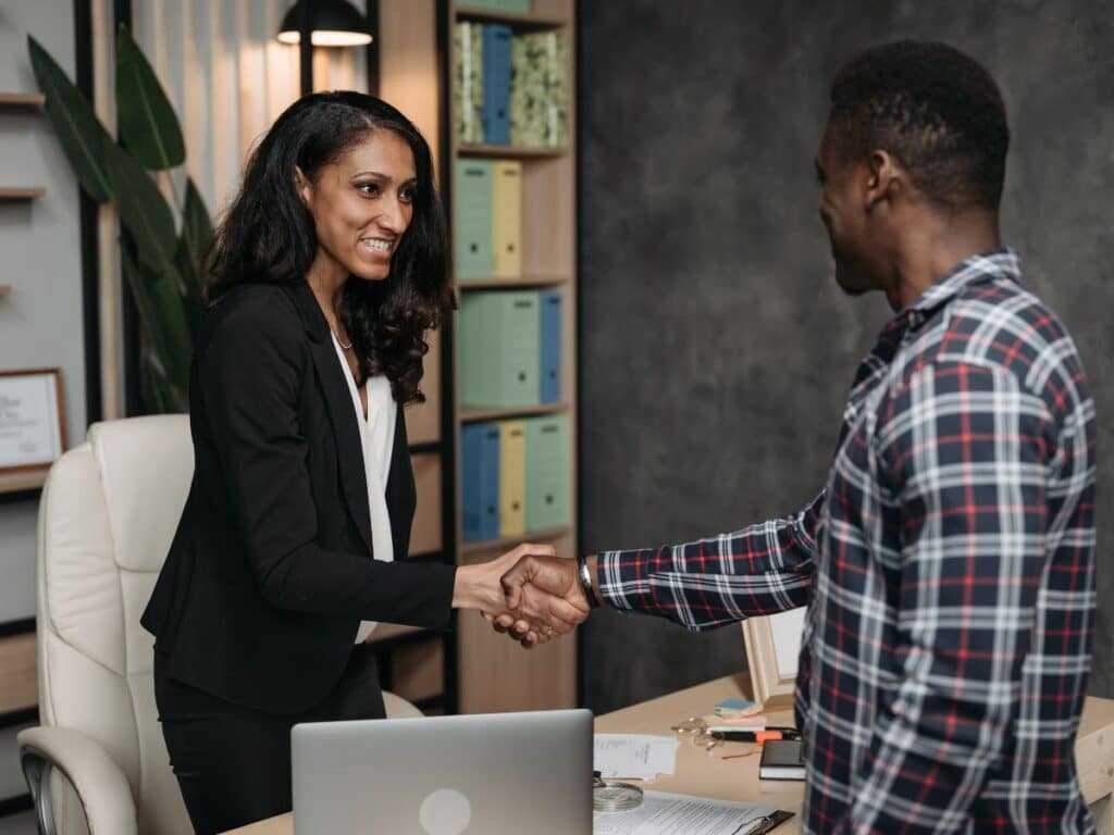 A personal injury lawyer meeting and shaking hands with her new client.
