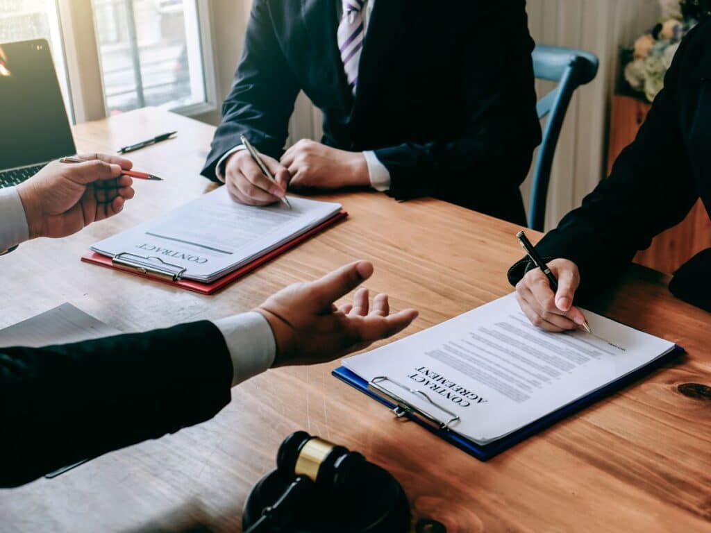 Two clients signing legal documents while sitting in front of their personal injury attorney.