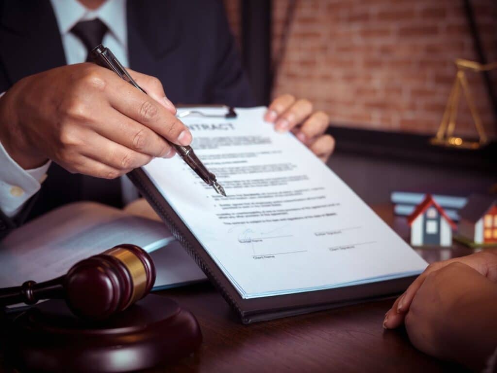 A personal injury lawyer presenting legal documents to his client and indicating where to sign them with a pen.