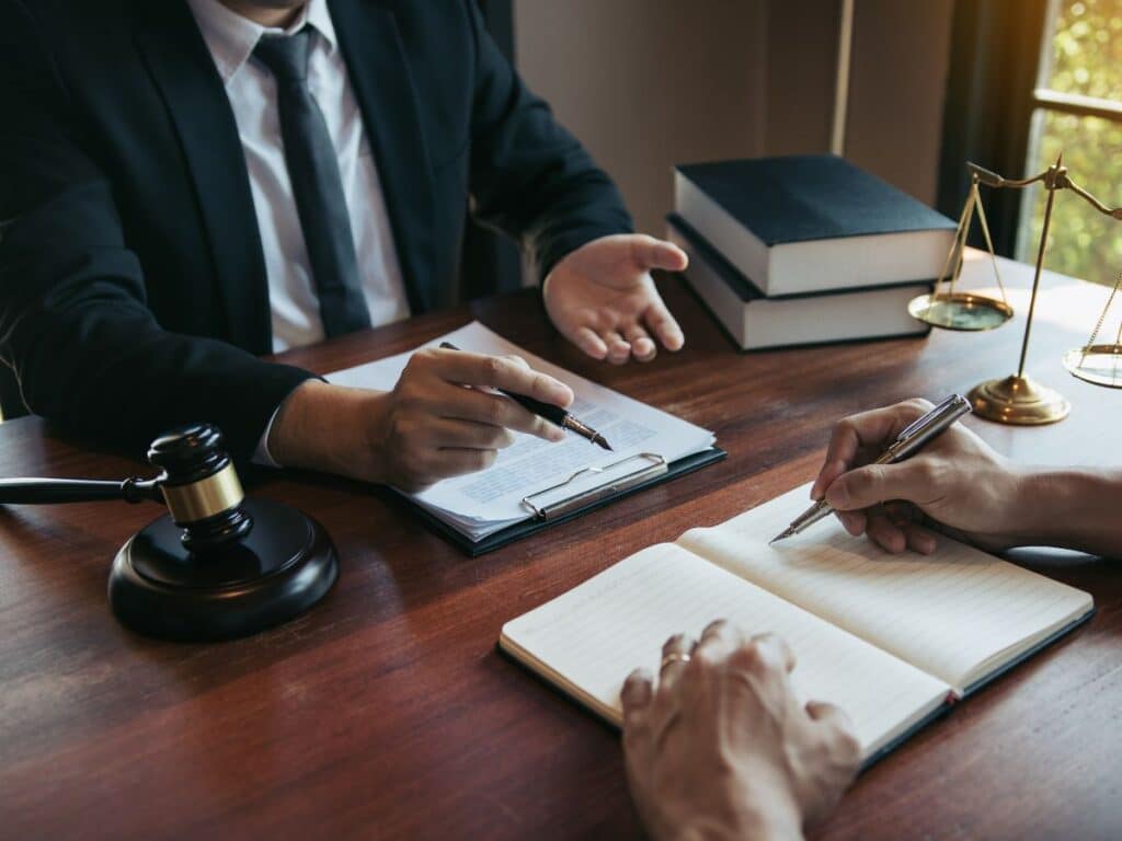 A personal injury lawyer explaining the claims process to his note-taking client.