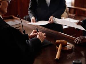 A personal injury attorney handing documents to a judge in a courtroom.