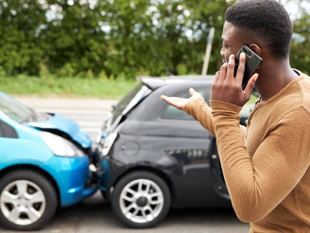 A man talking animatedly on the phone after a car accident.