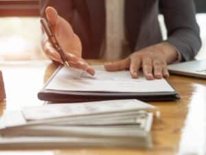 A personal injury lawyer pointing to stack of legal documents and money on a table.