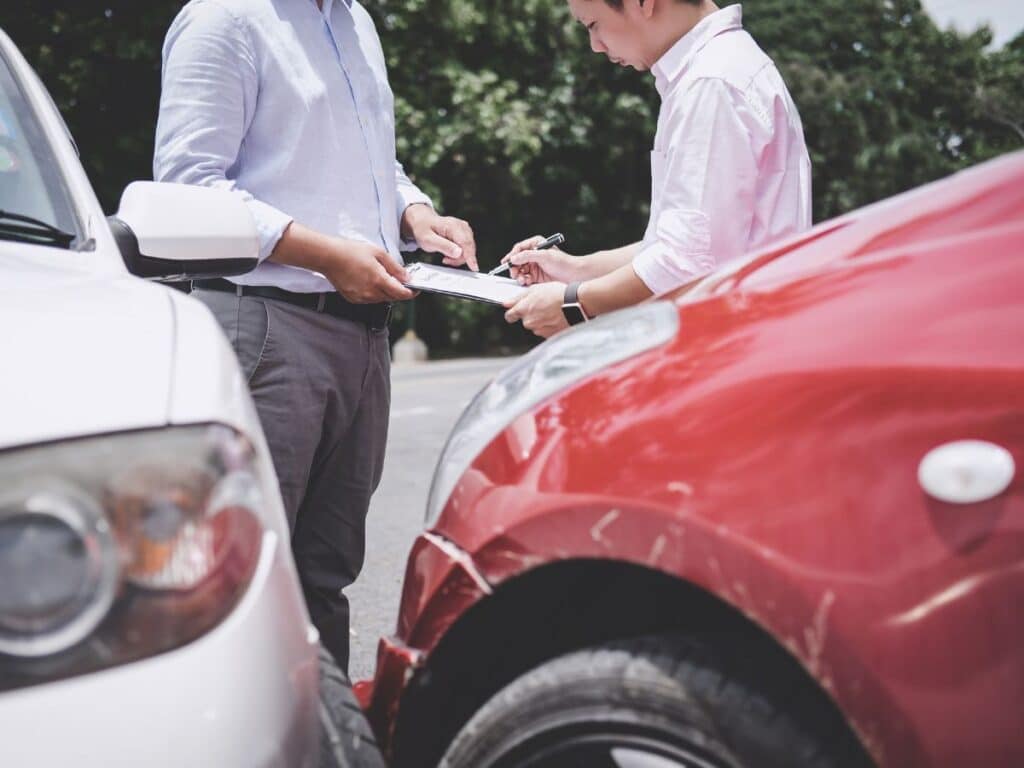 Two men exchanging insurance information after a car accident.