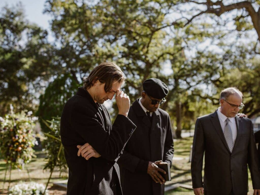 A man and woman, dressed in black, mourning their loved one at a funeral.