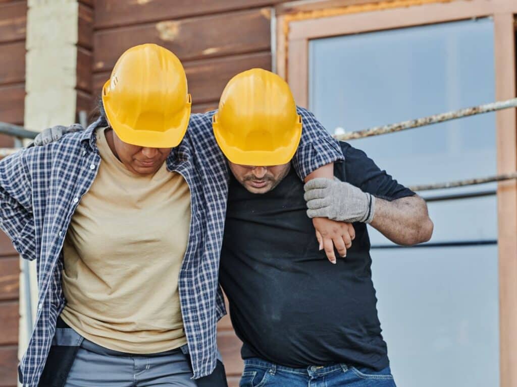 A construction worker supporting his injured coworker.