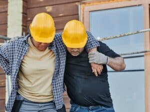 A construction worker supporting his injured coworker.
