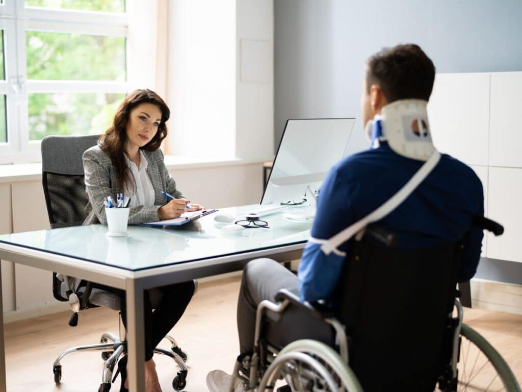 An injured man sitting across a desk from his workers' compensation attorney.