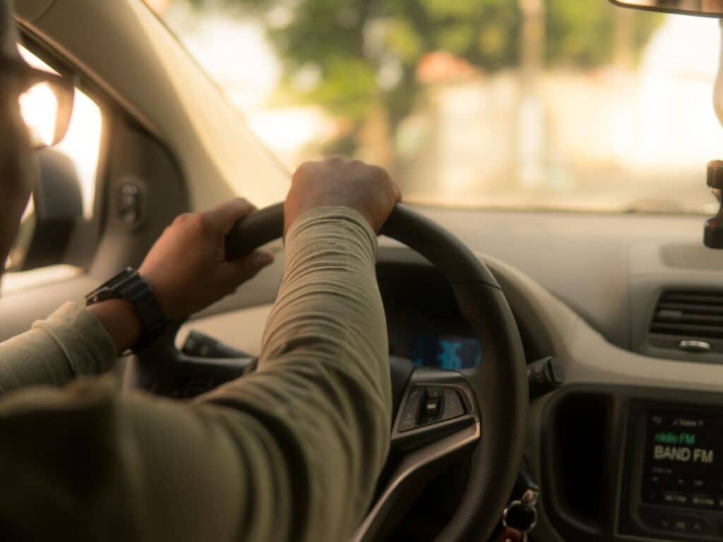 A rideshare driver sitting behind the wheel in his car.